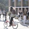 Jóvenes entrando al campus y chica en bici en primer plano