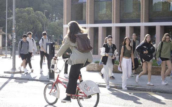 Jóvenes entrando al campus y chica en bici en primer plano