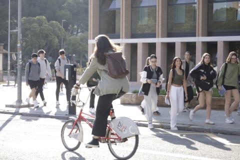 Jóvenes entrando al campus y chica en bici en primer plano